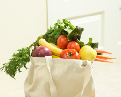 A cloth grocery bag overflowing with vegetables.