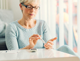 A senior woman testing her blood sugar at home.