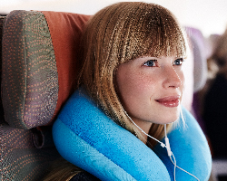  A woman on an airplane using a neck pillow.