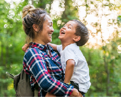 A mother holds her young son as they both laugh happily.