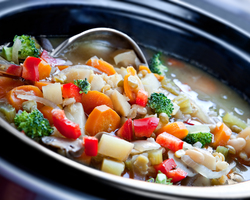 Close-up of a ladle and a slow cooker full of stew.