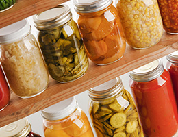 Rows of home-canned foods on wooden shelves.