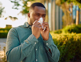 A man covers his nose with a tissue.