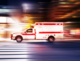 An ambulance drives fast on a dark street