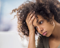 A woman with a headache rests her forehead on her hand