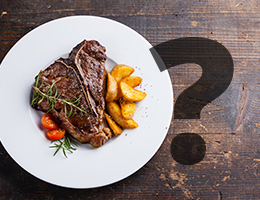 A plate of steak with roasted potatoes, tomatoes and rosemary on a wooden table, followed by a question mark. 