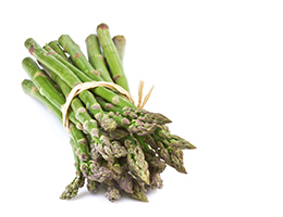 A bundle of asparagus, bound by a rubber band, sits against a white background. 