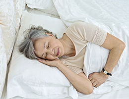 An older woman asleep in bed. 