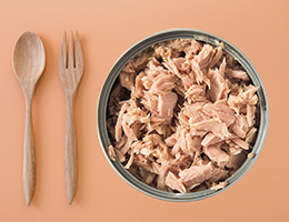 A bowl of tuna fish with a fork and spoon next to it.