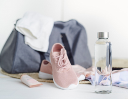 A bottle of water in front of a gym bag, shoes, etc.