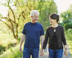 An older man and woman walk hand-in-hand