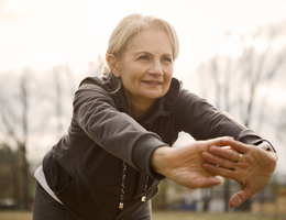 An older woman leans forward as she stretches