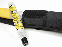 An EpiPen with a yellow label leans against its black carrying case.