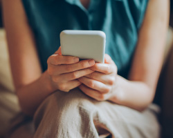 A woman holds a cellphone in her lap.