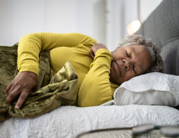  A woman lies on her side in a bed, sleeping.