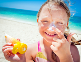 Young girl placing sunscreen on her nose.