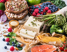 A spread of colorful foods, including berries, nuts and seeds, vegetables, and cheese.