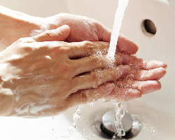 Soapy hands under a running faucet.