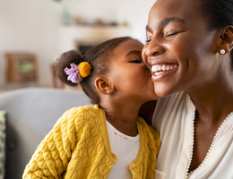 A little girl kisses a woman on the cheek