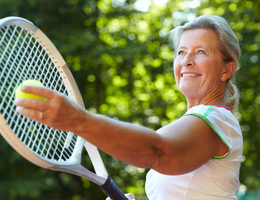An older woman prepares her tennis serve