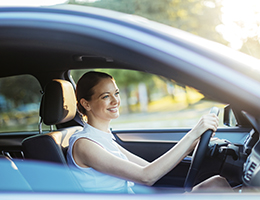 A smiling woman driving a car. 
