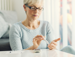 A woman checks her blood sugar at a coffee table.